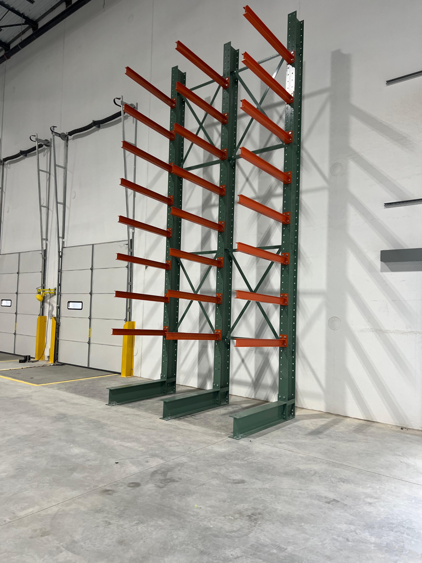Cantilever rack columns and arms installed along a warehouse wall